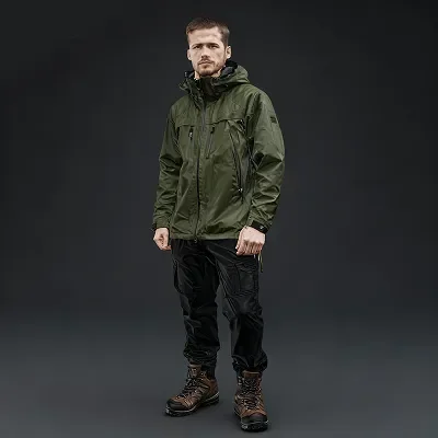 hiker wearing green waterproof jacket, black pants, and brown hiking boots.